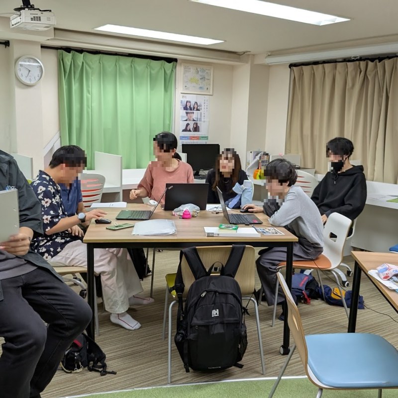中高生が教室で集まって活動する場面